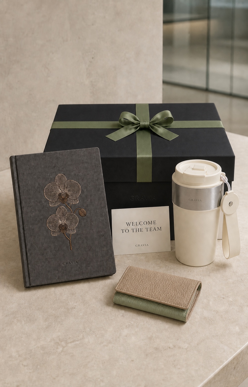 Employee welcome kit with a black GRAVIA gift box, orchid-embroidered notebook, travel cup, leather card holder and welcome card
